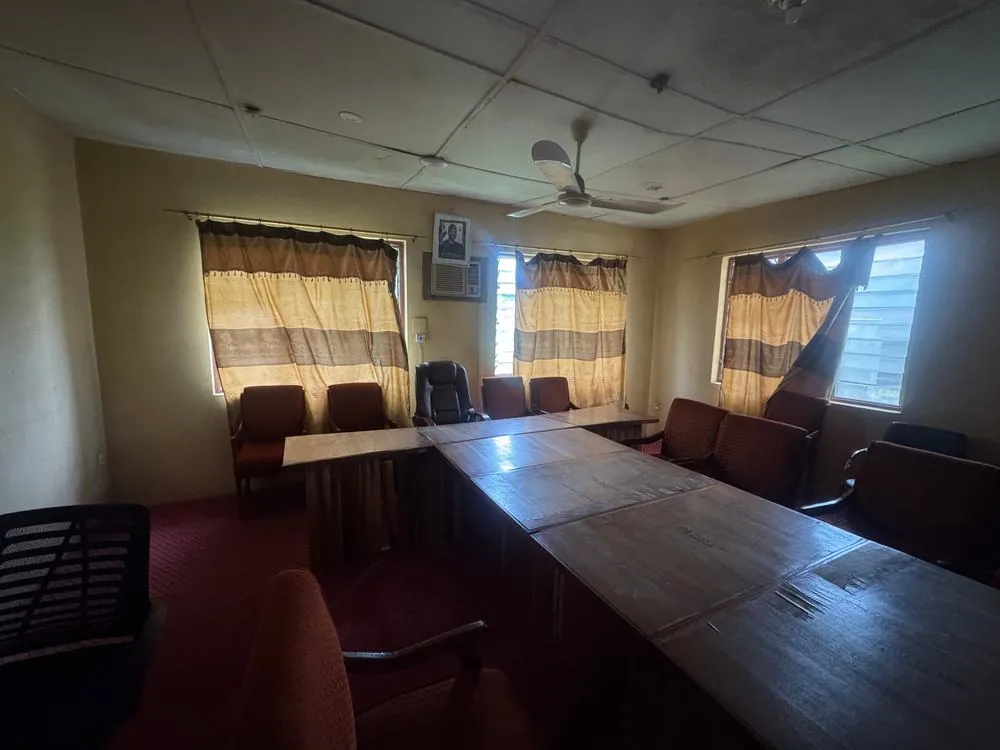 The meeting room before: worn table tops, mismatched chairs, old curtains and a dim tiled ceiling